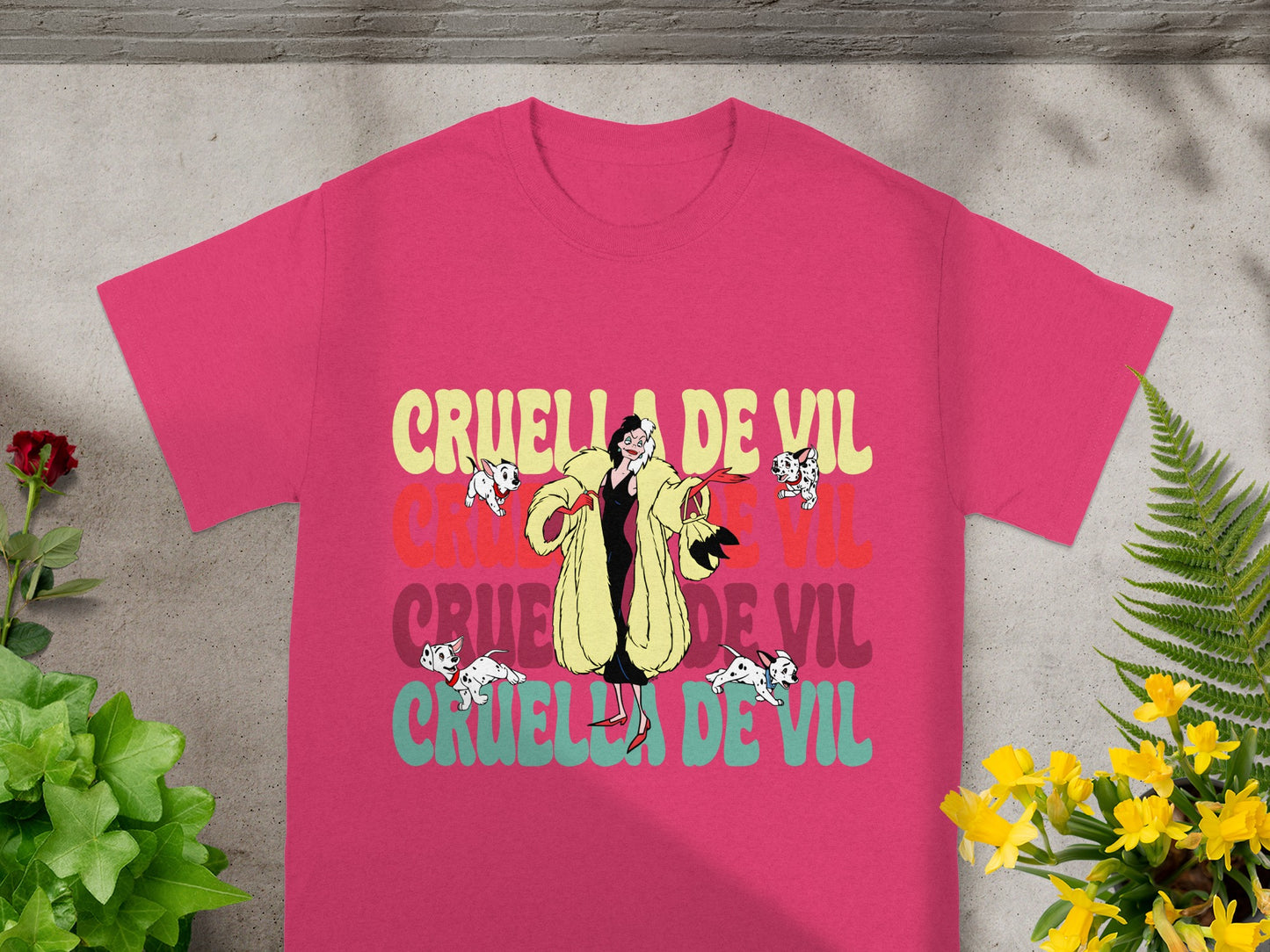 Pink t-shirt with "Cruella De Vil" in layered colorful text.