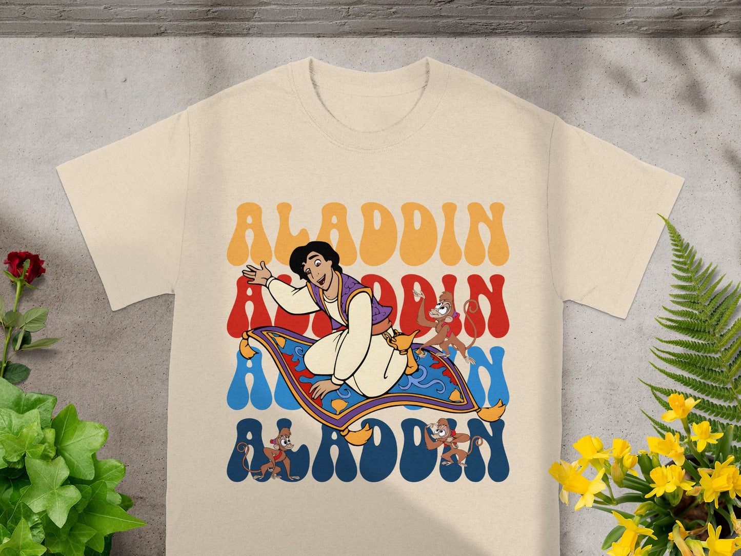 Aladdin, Abu, and magic carpet graphic on a cream t-shirt.