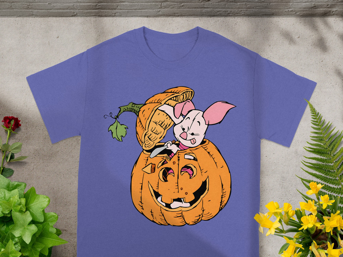 Piglet peeks from a carved Halloween pumpkin on a purple t-shirt.