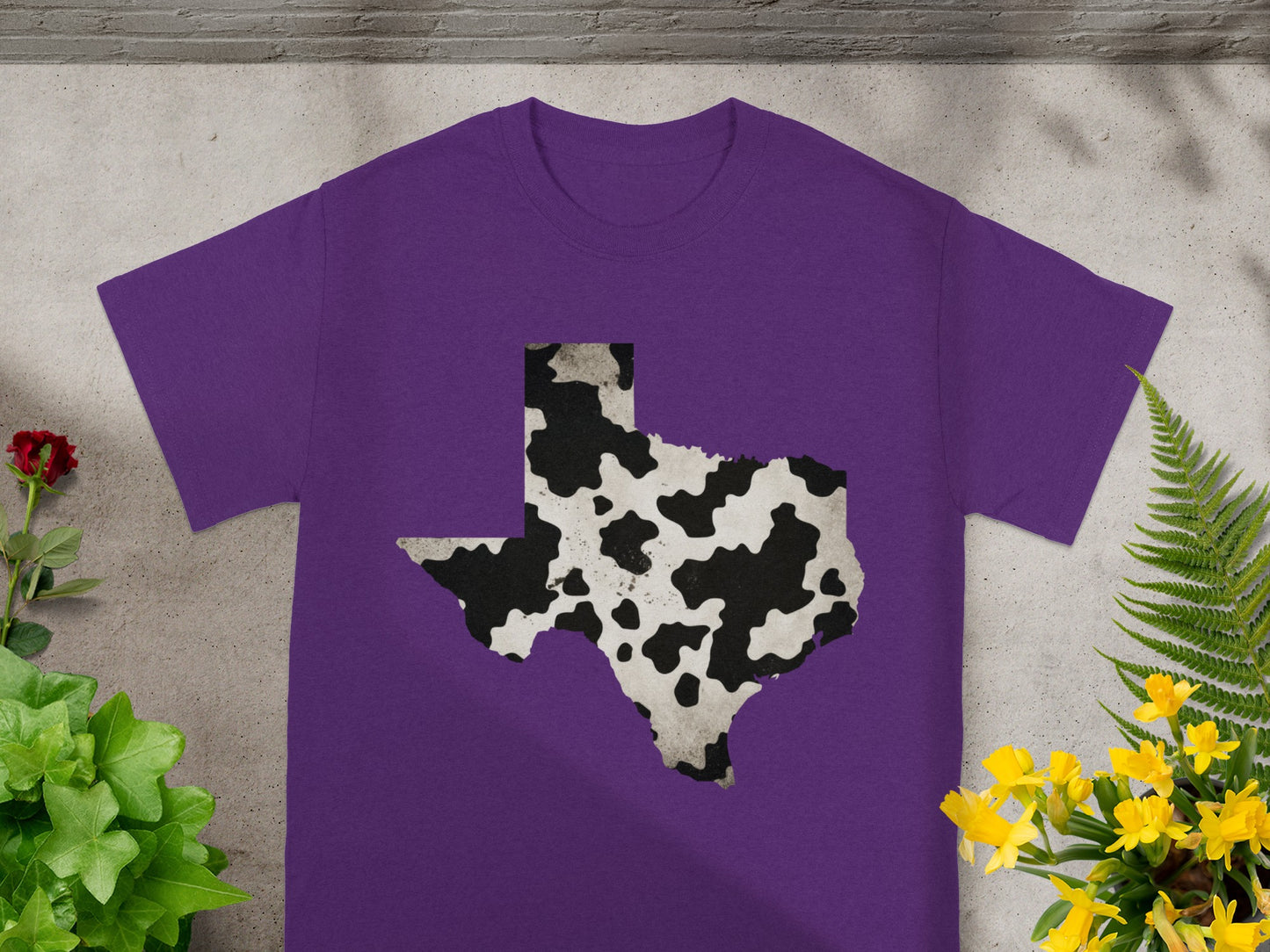 Purple t-shirt with a cow print Texas outline graphic.