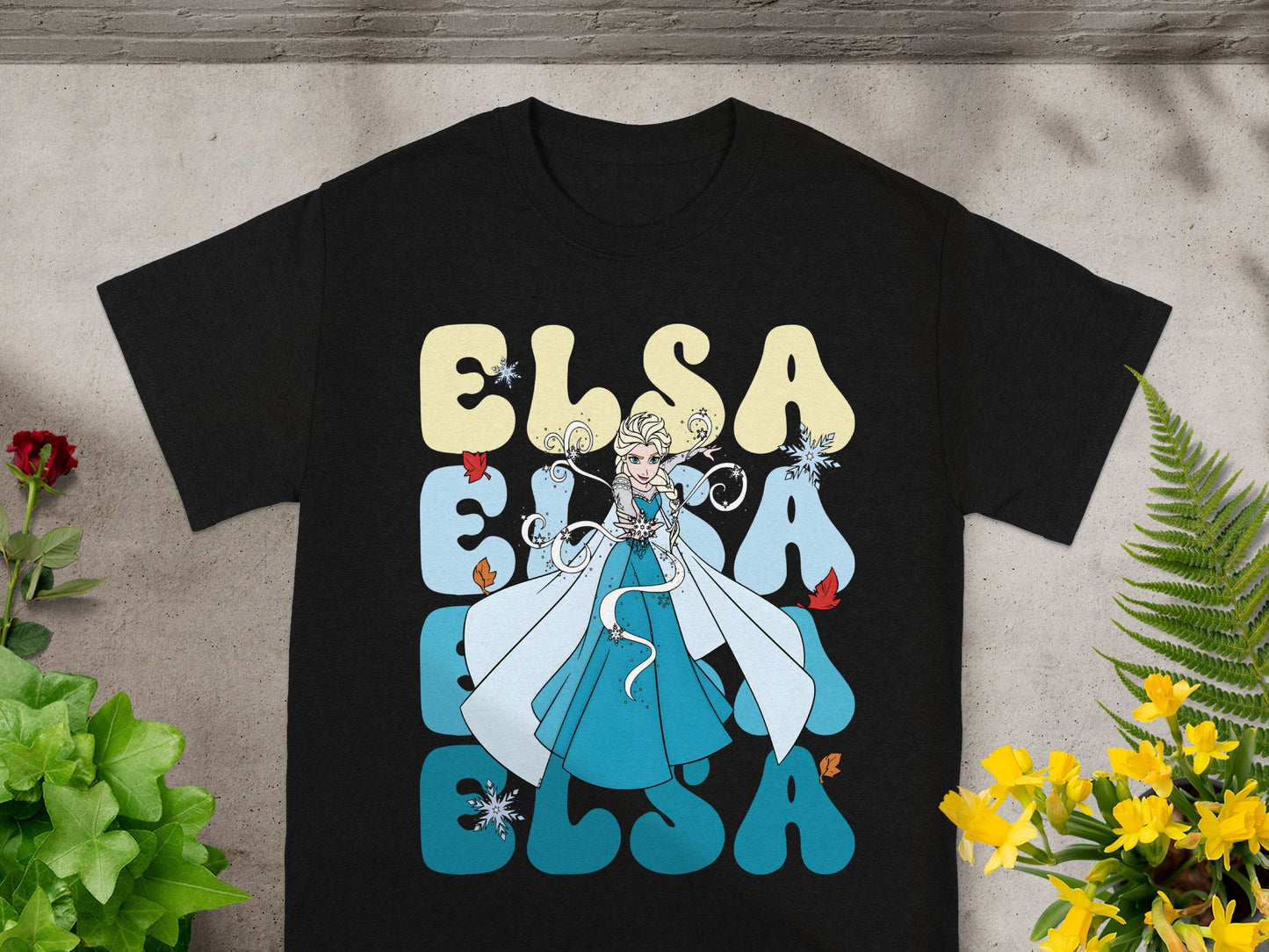 Black t-shirt with Elsa from Frozen graphic and repeating "Elsa" text.