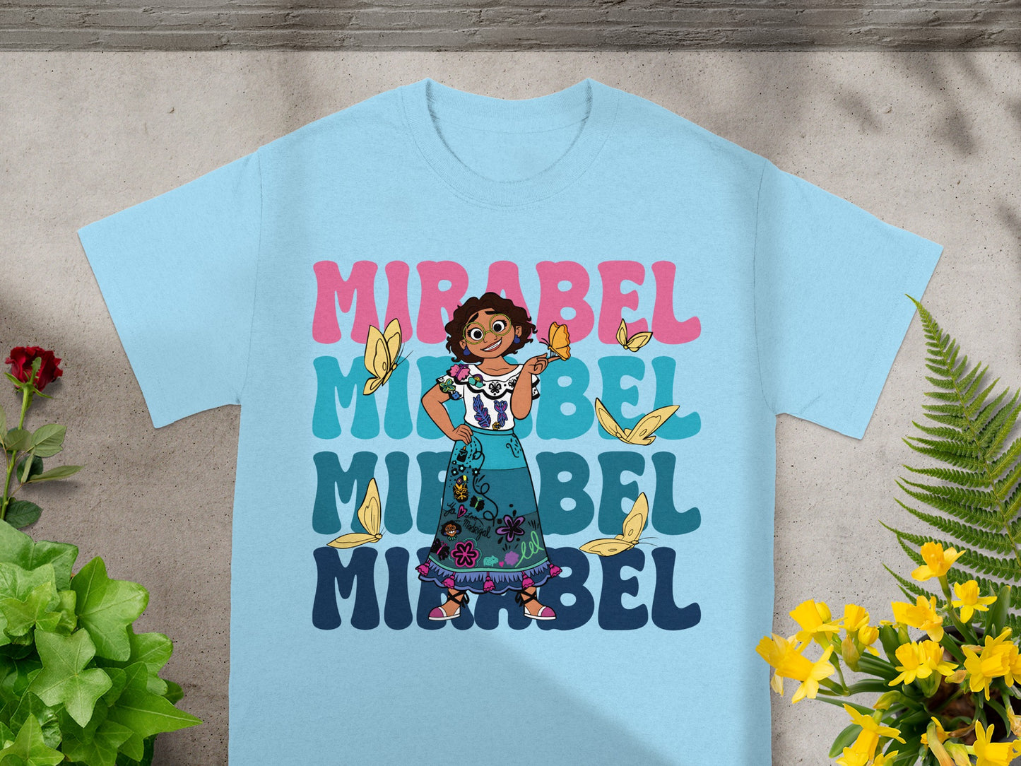 Light blue t-shirt with "Mirabel" in colorful text and butterflies.
