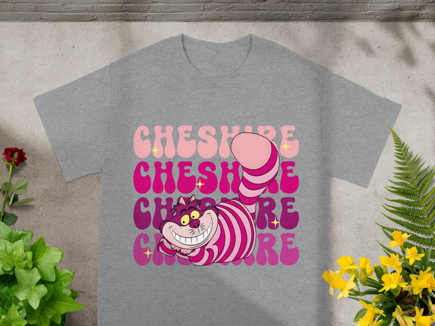 Cheshire Cat graphic on a grey t-shirt with pink and purple text.