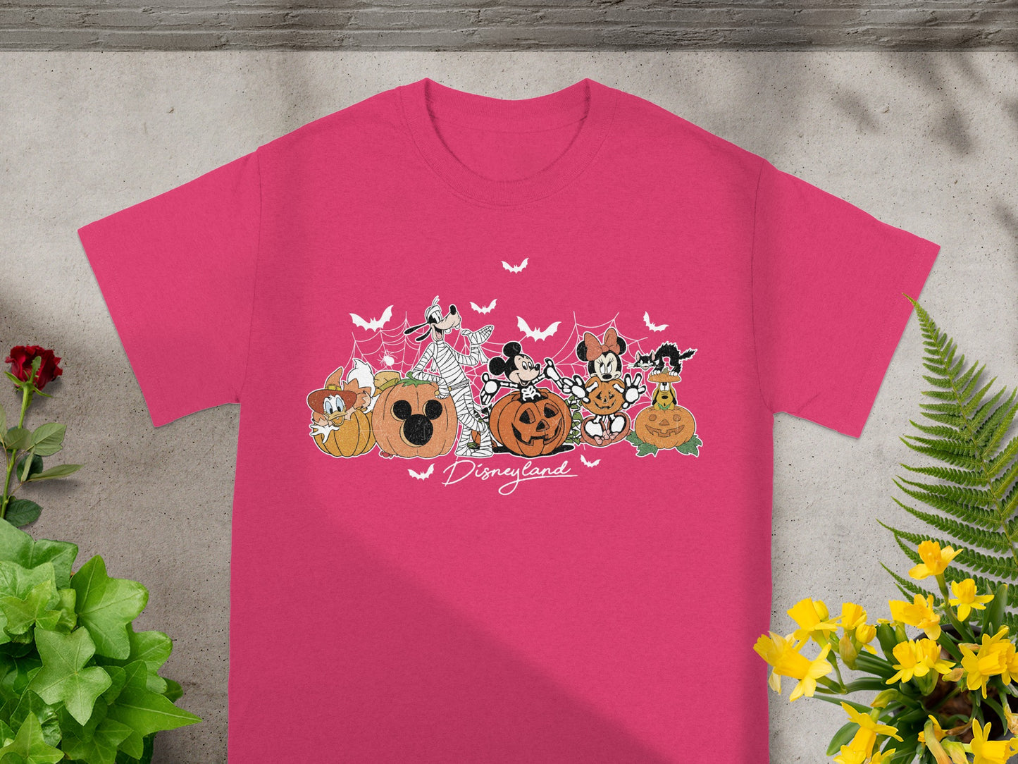 Pink t-shirt with Disney characters and pumpkins in Halloween theme with "Disneyland" text.