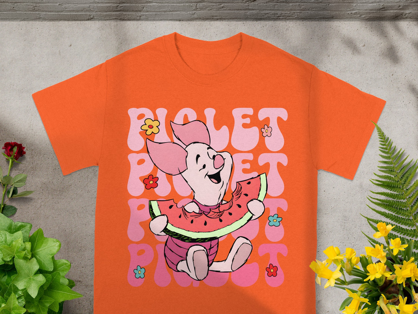 Orange t-shirt with Piglet eating watermelon, surrounded by flowers.