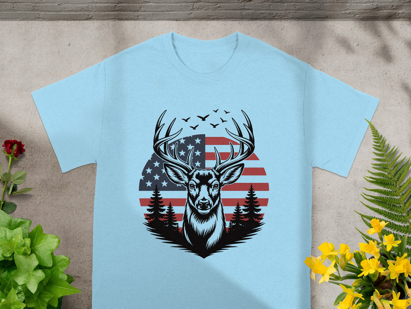 Deer head graphic with American flag and pine trees on a light blue t-shirt.