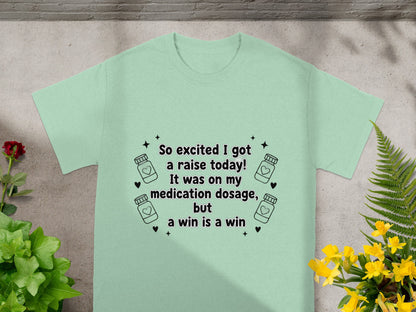Light green t-shirt with "So excited I got a raise today! It was on my medication dosage, but a win is a win" text.