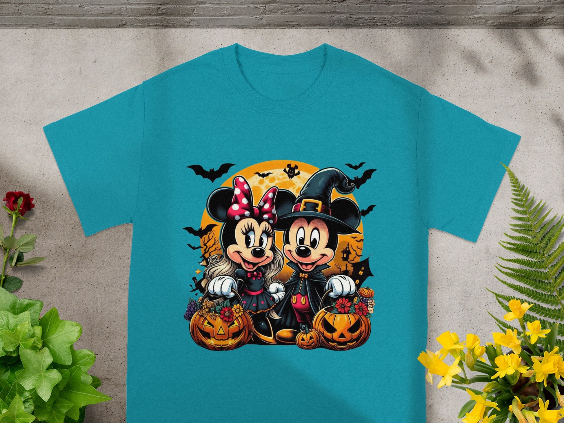 Mickey and Minnie Mouse in Halloween costumes with pumpkins and bats on a teal shirt.