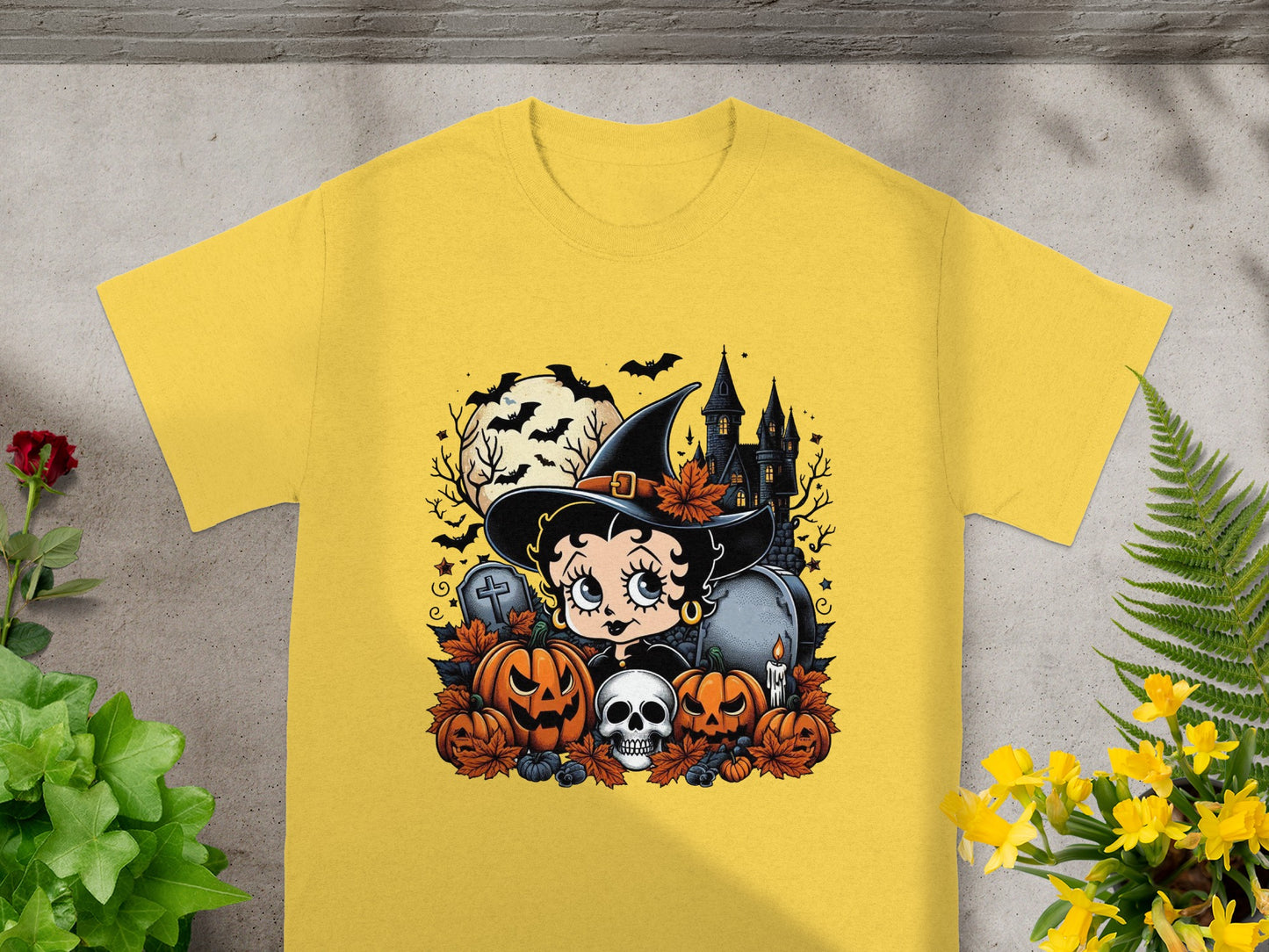 Betty Boop as a witch with pumpkins, skull, and haunted house on yellow t-shirt.