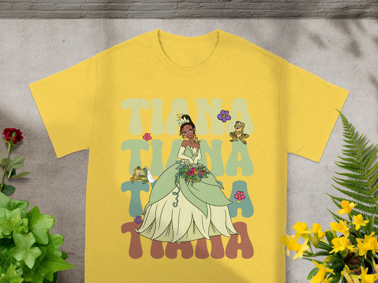 Yellow t-shirt with Tiana, Naveen, and Ray graphic.