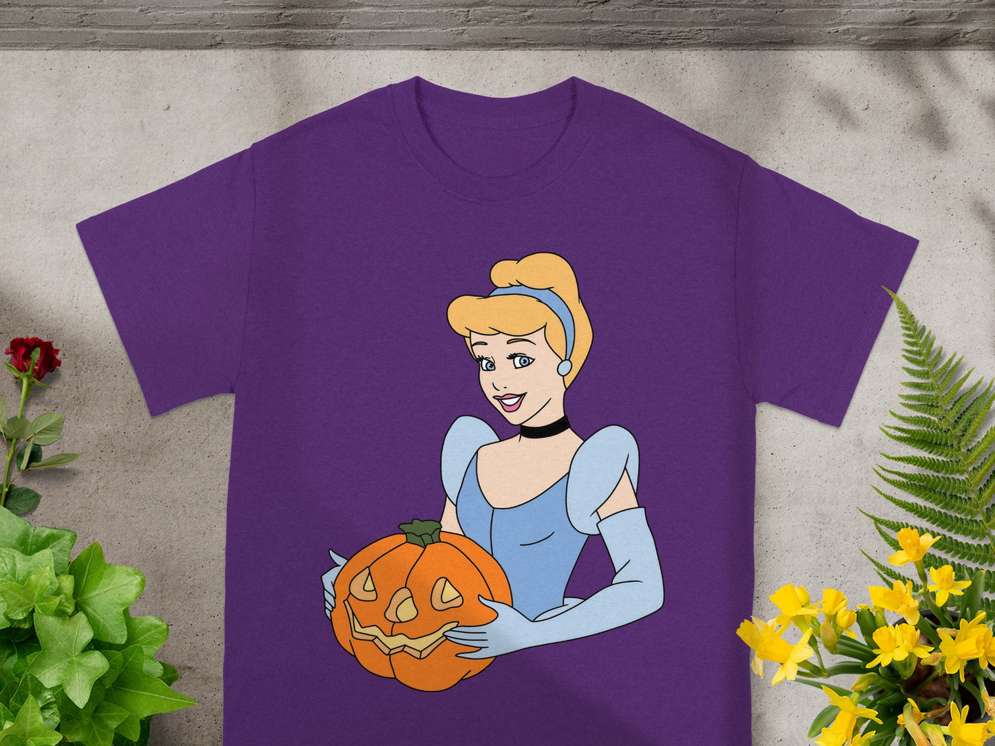 Cinderella in a blue dress holding a jack-o'-lantern on a purple t-shirt.