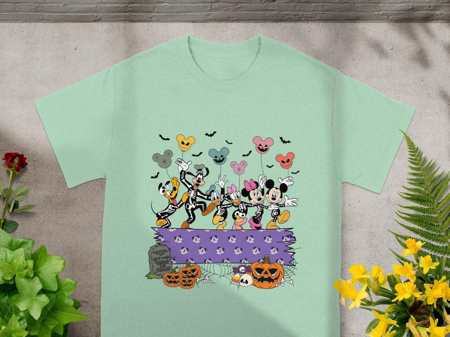 Mickey Mouse characters in skeleton costumes dance with Halloween balloons and pumpkins.