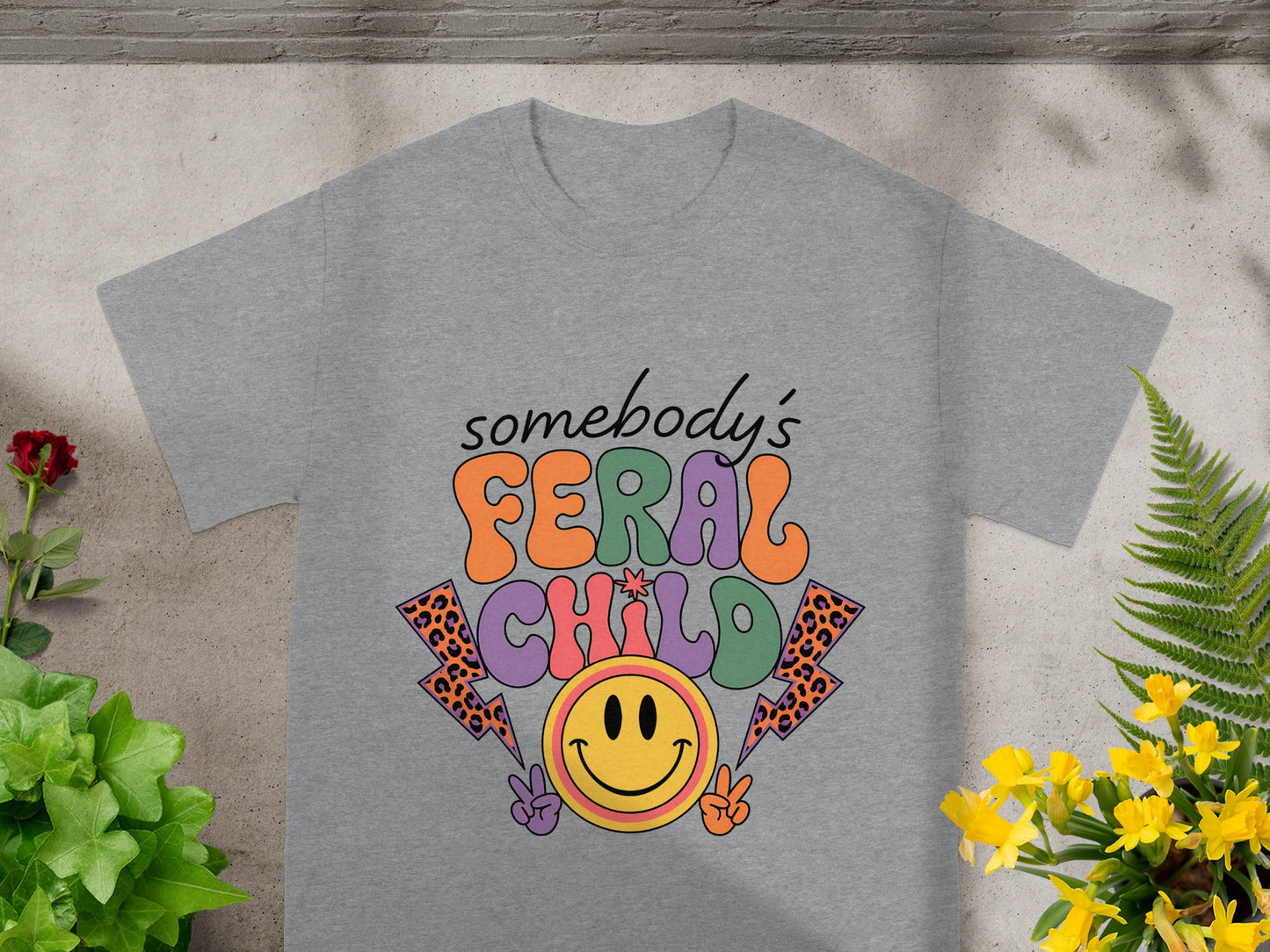 Grey t-shirt with "somebody's FERAL CHILD" text, smiley face, and lightning bolts.