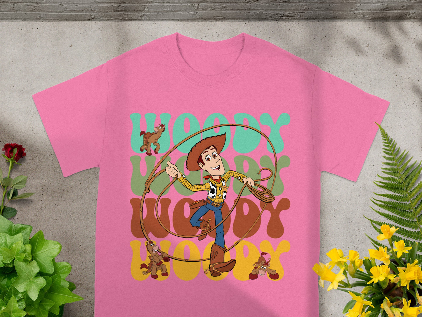 Pink t-shirt with Woody from Toy Story holding a lasso, with "WOODY WOODY" text.
