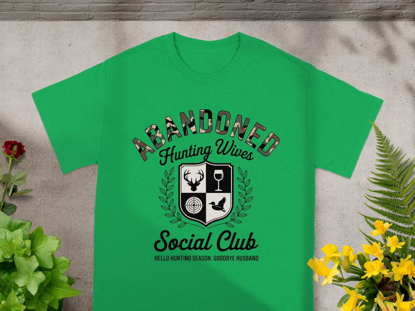 Green t-shirt with "ABANDONED Hunting Wives Social Club" graphic and hunting imagery.