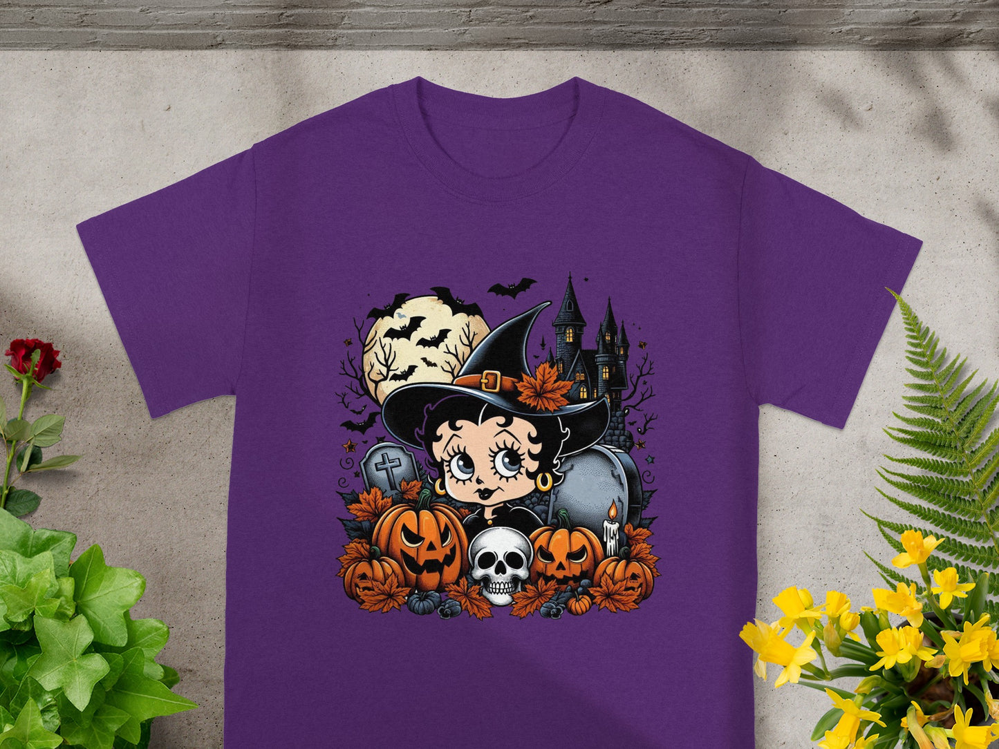 Betty Boop witch graphic with pumpkins, skull, haunted house, and moon on purple t-shirt.