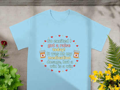Light blue t-shirt with "So excited I got a raise today! It was on my medication dosage, but a win is a win" text.