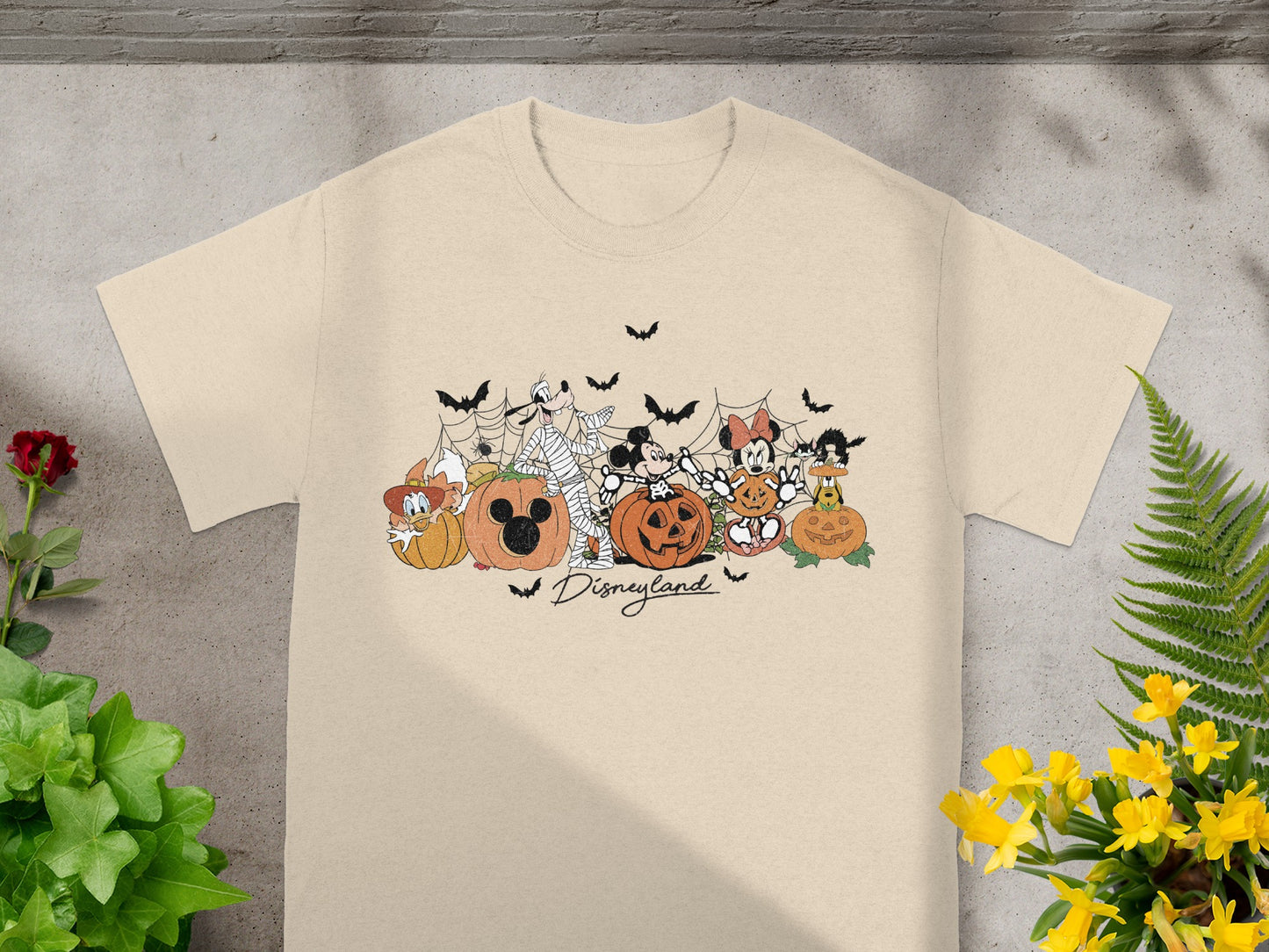Disneyland Halloween graphic with Disney characters and pumpkins on a light tan shirt.